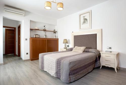 a white bedroom with a bed and a night stand at Reina's in Vejer de la Frontera