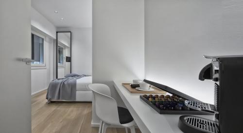 Luxury Suites Collection - SHANTUNG Double Room في ريتشيوني: غرفة بيضاء بسرير وطاولة وكراسي