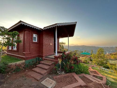 a small red brick house with stairs in front of it at Holygram Krushi Paryatan in Panchgani