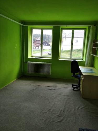 een groene kamer met een bureau en 2 ramen bij Pronájem bytu 3+kk in Železná Ruda