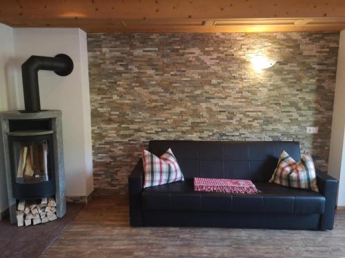 a living room with a black couch and a brick wall at Chalet Innertal in Inneralpbach