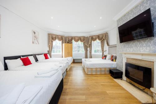 Habitación con 4 camas y chimenea. en Larger Groups Canary Wharf Apartment with Large Garden & Parking, en Londres