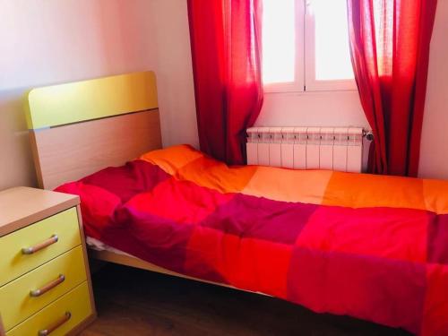 a bedroom with a bed with a red and orange blanket at Casa del Río in Móstoles