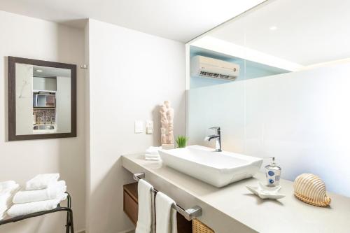 Un baño blanco con lavabo y espejo. en Harbor 3008 Amazing beach front condo by Moikkarentals, en Puerto Vallarta