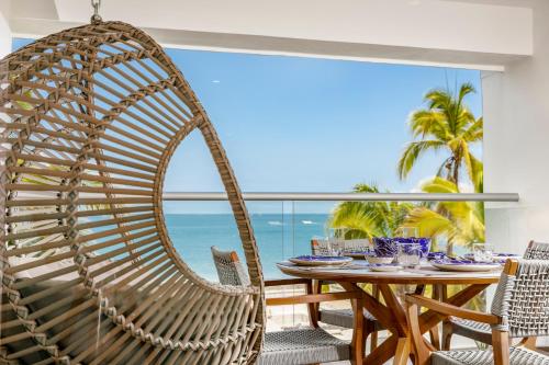a rattan swing chair in a dining room with a table at Harbor 3008 Amazing beach front condo by Moikkarentals in Puerto Vallarta