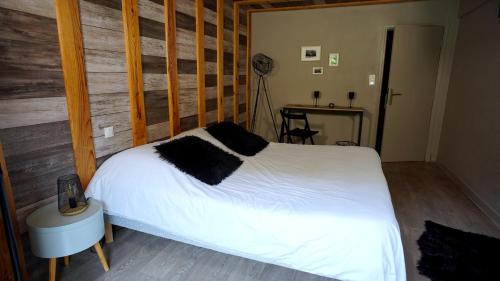 a bedroom with a white bed and a wooden wall at La Sapinière St Lary Soulan in Saint-Lary-Soulan