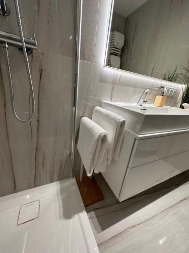 uma casa de banho branca com um lavatório e um espelho em Shelter Luxury Apartament em Rogowo