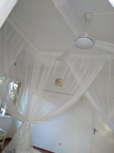 a bedroom with a white curtain on a ceiling at Ilha Azul House in Ponta do Ouro