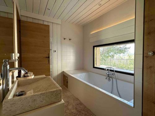 een badkamer met een bad, een wastafel en een raam bij Le Nid des Amis -Villa, jardin, vue à la montagne in Saint-Auban