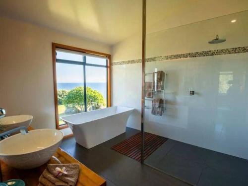 a bathroom with a tub and a sink and a window at King Tide House - Ocean Views in Burnt Pine