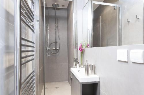 une salle de bain blanche avec une douche et un lavabo dans l'établissement LivinParis - Luxury 3 Bedrooms Grands-Boulevards I, à Paris
