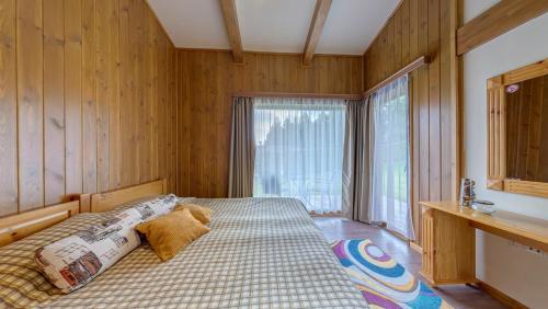 Un dormitorio con una cama con paredes de madera y una ventana en Boutique Holiday Pirin Golf en Razlog
