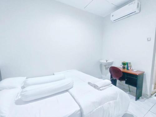 Dieses weiße Zimmer verfügt über ein Bett und einen Schreibtisch. in der Unterkunft Kost Griya Asri by ecommerceloka in Jakarta