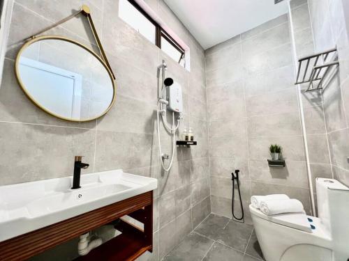 a bathroom with a sink and a mirror and a toilet at Klebang Melaka - ADA villa - 12-15pax/4room/Pool in Melaka