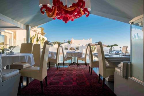 a restaurant with tables and chairs and a chandelier at Greco Philia Hotel Boutique in Elia Beach