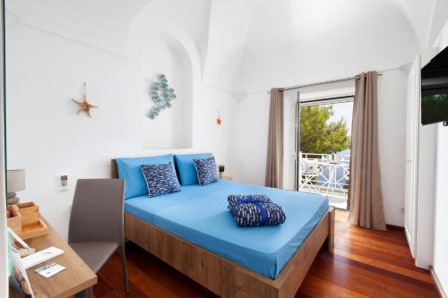 a bedroom with a blue bed and a large window at Faraglionensis MonaconeHouse Villa in Capri