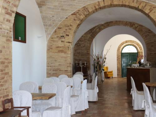 Habitación con sillas blancas y pared de ladrillo. en IL CASALE B&B en Cupello