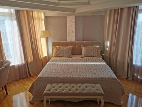 a bedroom with a large bed with a bench in it at Stunning new design apartment next to park in Chişinău
