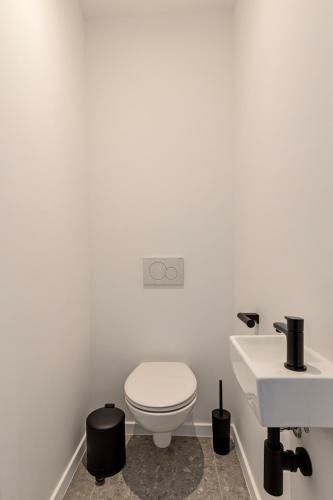 a white bathroom with a toilet and a sink at Märch - Mechelen Goat 21 in Mechelen