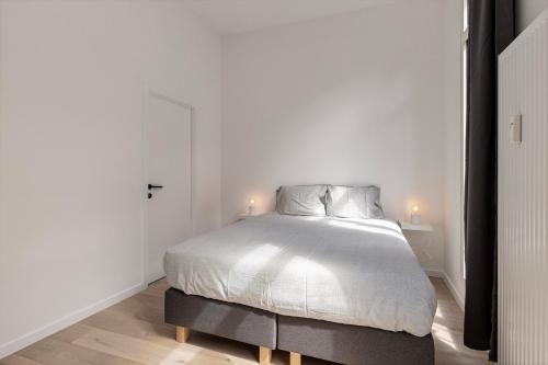 a white bedroom with a bed with two lamps on it at Märch - Mechelen Goat 21 in Mechelen