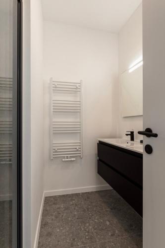 a white bathroom with a sink and a mirror at Märch - Mechelen Goat 21 in Mechelen