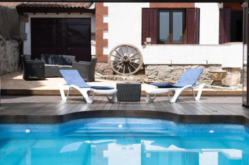 two chairs and a swimming pool in front of a house at UN PASEO POR LAS NUBES in El Espinar