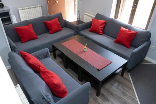 a living room with couches and a table with red pillows at UN PASEO POR LAS NUBES in El Espinar