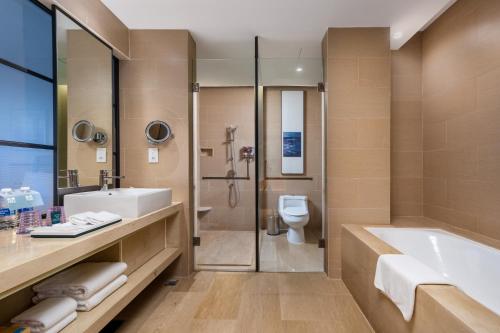 a bathroom with a tub and a sink and a toilet at Four Points by Sheraton Guangdong, Heshan in Heshan