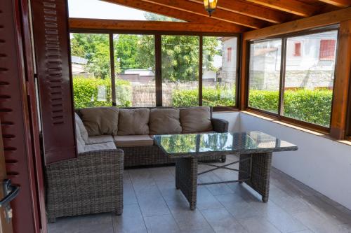 a screened in porch with a couch and a glass table at UN PASEO POR LAS NUBES in El Espinar