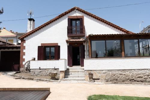 a white house with windows and a balcony at UN PASEO POR LAS NUBES in El Espinar