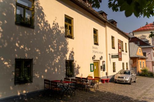 a white building with tables and chairs on a street at Penzión Príjemný Oddych in Banská Štiavnica
