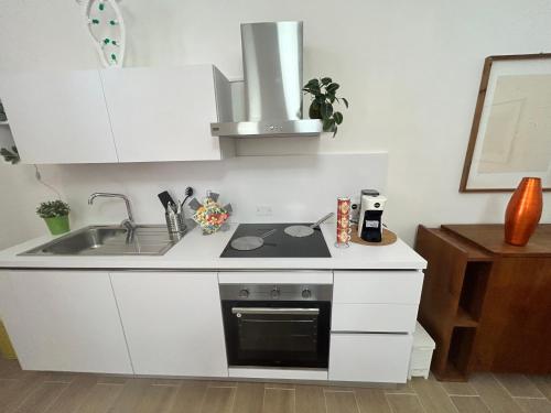 una cucina bianca con lavello e fornello di Volare House a Bari