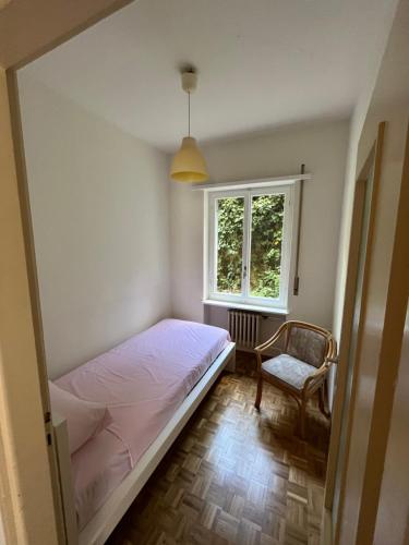 ein Schlafzimmer mit einem Bett, einem Stuhl und einem Fenster in der Unterkunft Cube 1B Flat in Lugano