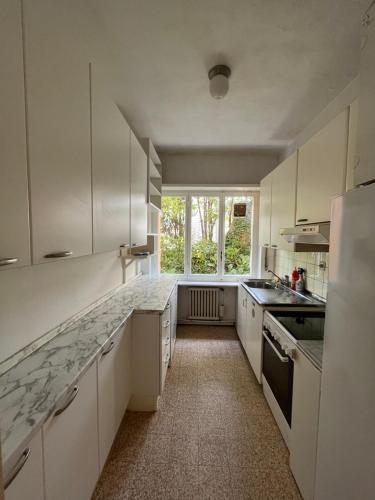 eine große Küche mit weißen Schränken und einem Fenster in der Unterkunft Cube 1B Flat in Lugano