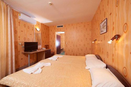 een slaapkamer met 2 bedden en een bureau met een computer bij Hotel Smolyan in Sunny Beach