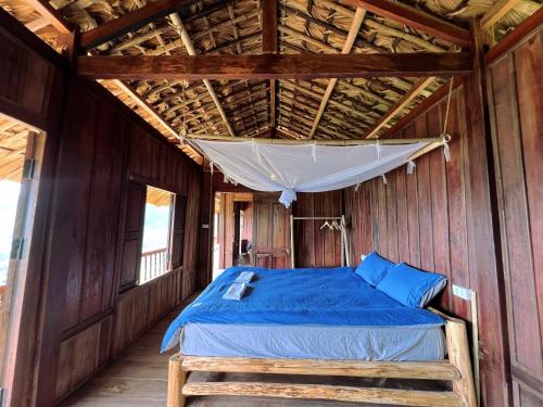 een bed in een houten kamer met een baldakijn bij Lagom Su Phi Retreat in Hoàng Su Phì