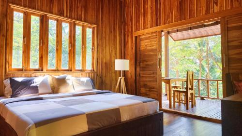 um quarto com uma cama e uma grande janela em Baan Bhuwann Forest Chalet em Ko Phangan
