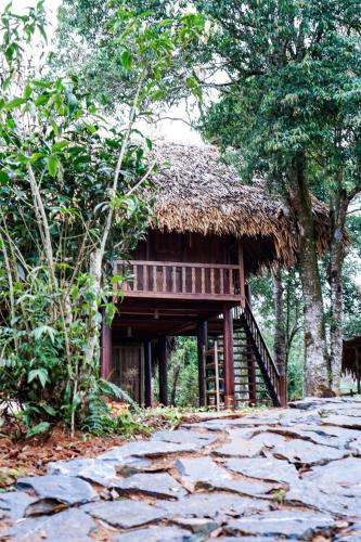 a house with a thatched roof and a stone floor at Lagom Su Phi Retreat in Hoàng Su Phì