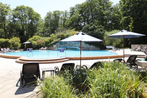 a swimming pool with two umbrellas and chairs at Hotel Bernstein Prerow in Prerow