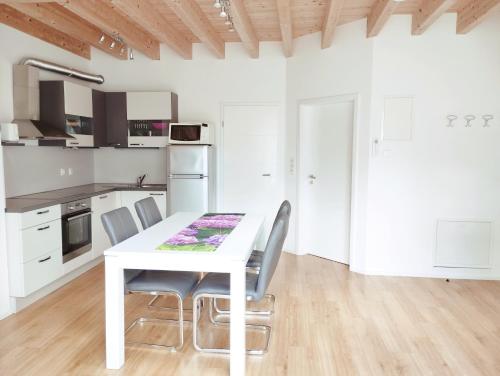 biała kuchnia z białym stołem i krzesłami w obiekcie Apartments Wallas w mieście Bovec