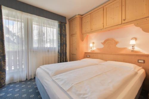 a bedroom with a large white bed and a window at Garnì La Dorada in Colfosco