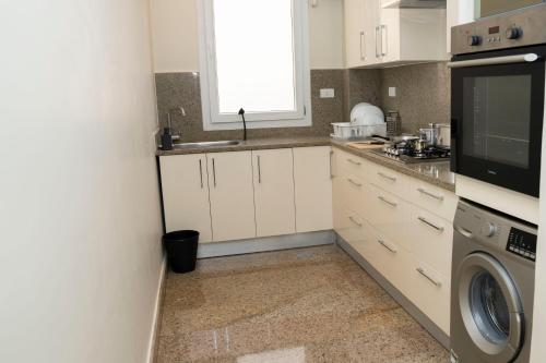 a kitchen with white cabinets and a washer and dryer at Dream House in 6th Of October