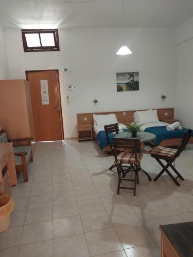 Cette chambre comprend une table, des chaises et un lit. dans l'établissement PHILIPPOS STUDIOS & APT, à Lindos