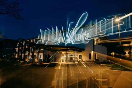 a building with a neon sign in a parking lot at Aqua Blu Hotel in Bad Füssing