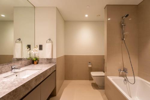 a bathroom with a sink and a tub and a toilet at INA Homes - Act 1 Full Burj Khalifa and Fountain Views in Dubai