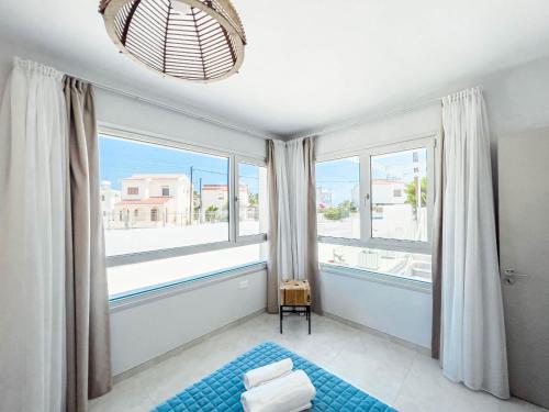 1 dormitorio con ventanas grandes y alfombra azul en Geo Panoramic Villa +Pool +Game Room +Gym en Protaras
