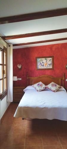 1 dormitorio con cama blanca y pared roja en Refugio La Presa, en Chulilla