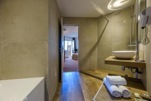 een badkamer met een wastafel en een bad bij Hotel Le Tilbury in Porto-Vecchio
