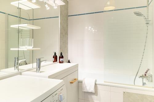 une salle de bain blanche avec deux lavabos et une douche dans l'établissement L'Ingénieux - Appt près de la Place Zola, à Nantes