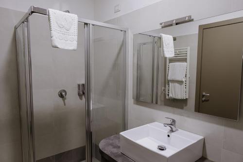 ein weißes Bad mit einem Waschbecken und einer Dusche in der Unterkunft Queen Hotel in Sesto San Giovanni